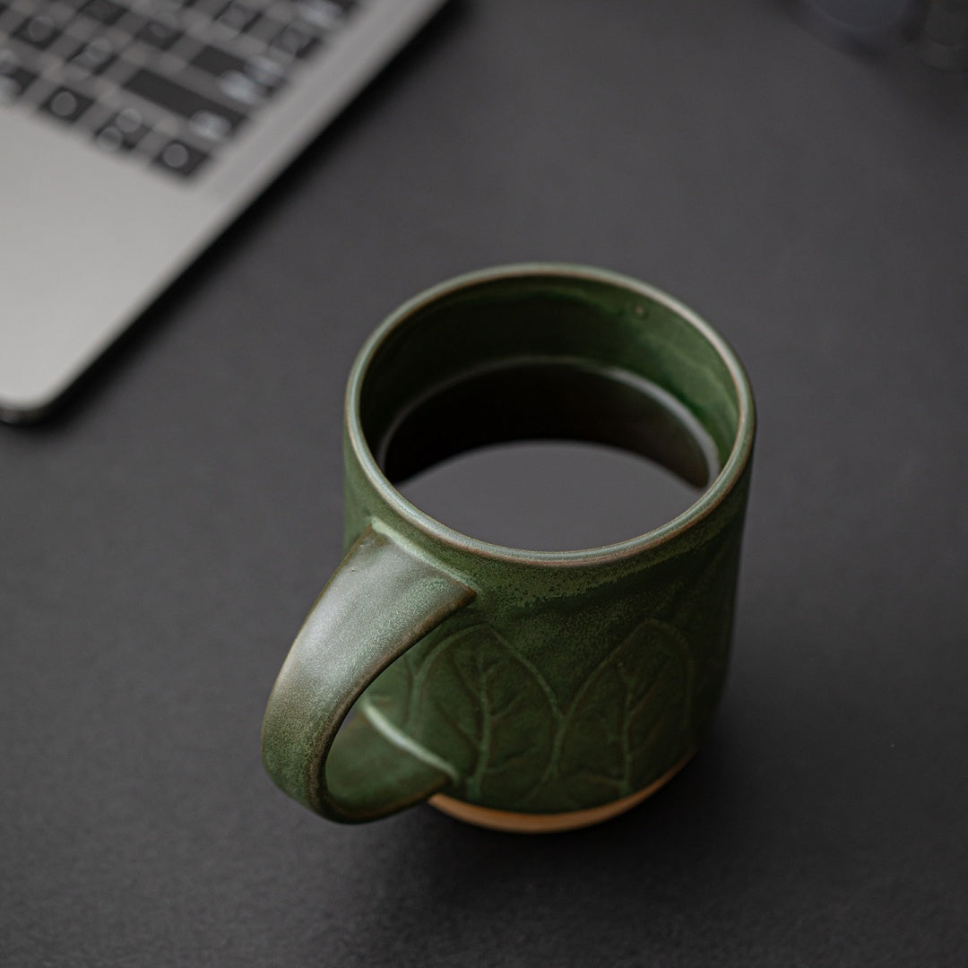 Person holding Ceravor large leaf relief green ceramic mug with one hand