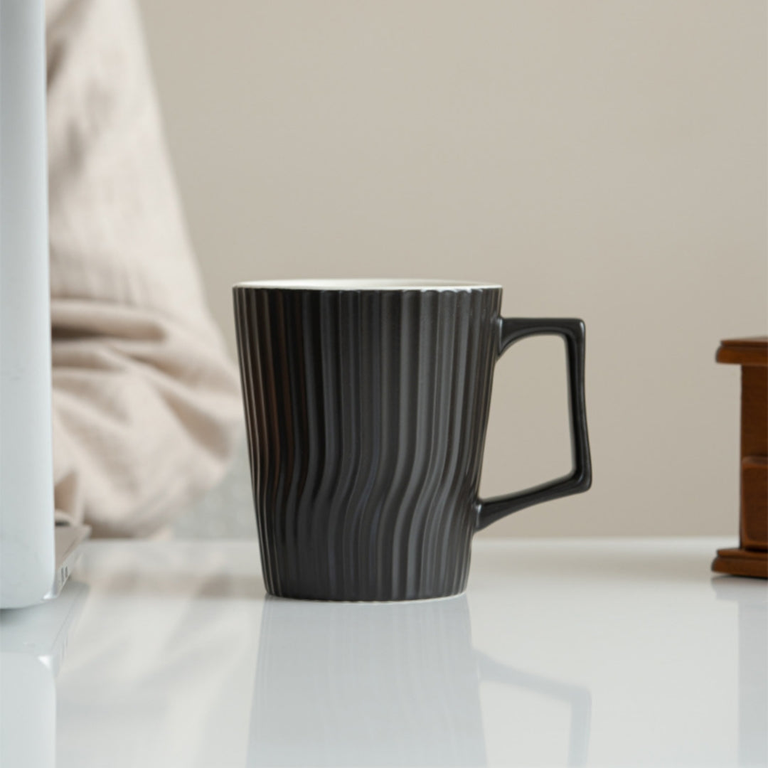 Ceravor black and white ribbed ceramic coffee mugs side by side on table