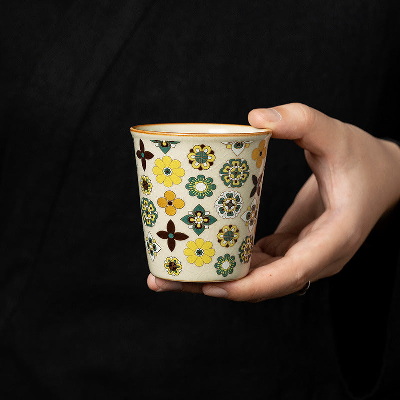 Hand holding Ceravor retro floral ceramic cup against dark background