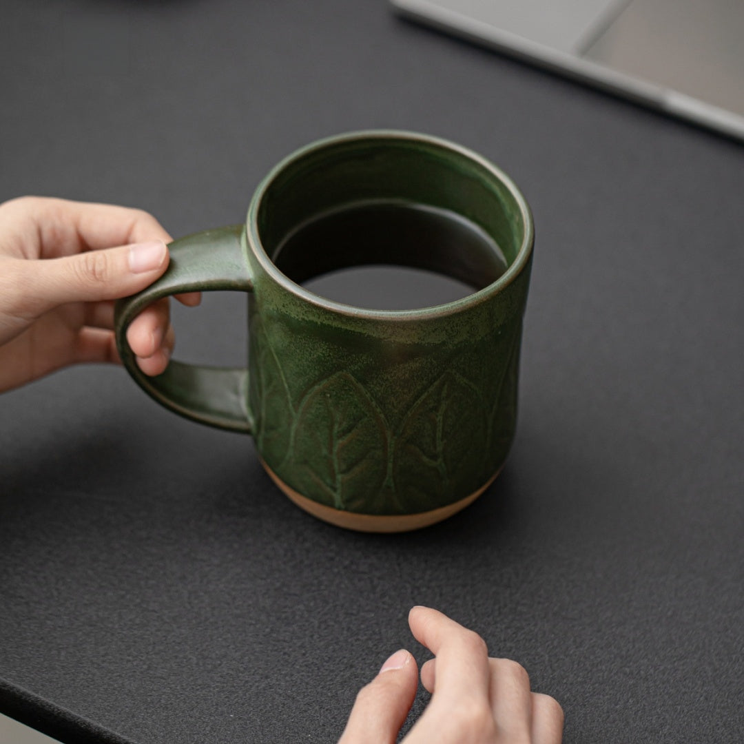 Person holding Ceravor green ceramic mug with dark coffee over a table